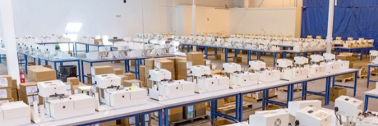 Rows of UniProd machines writing on tables across a production floor